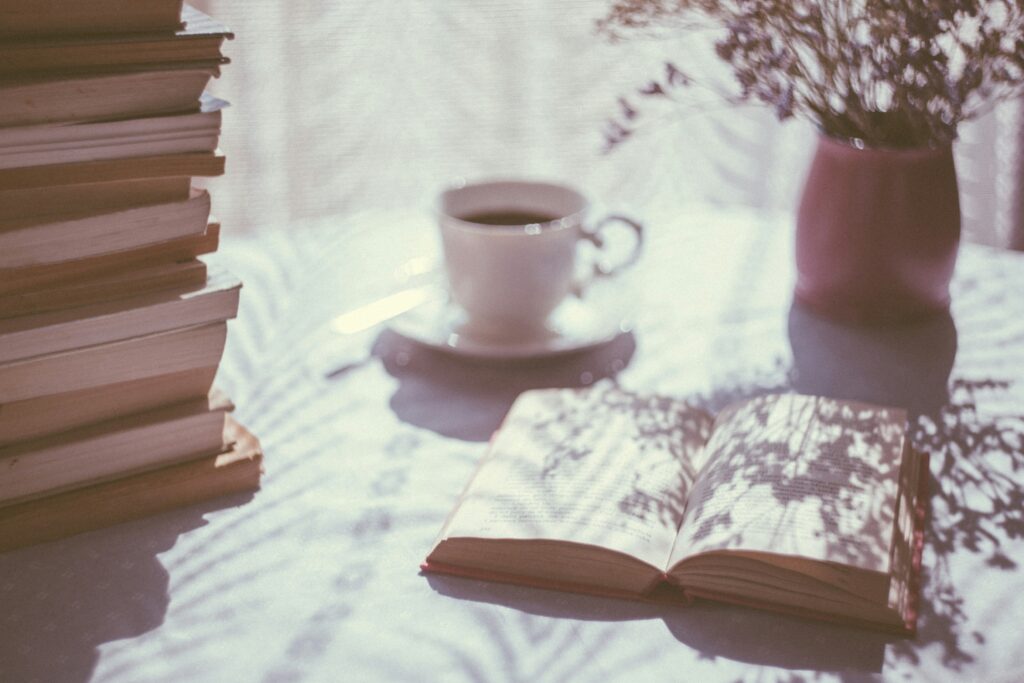 Someone enjoying a cup of tea while reading a book in the morning light, promoting productivity boost